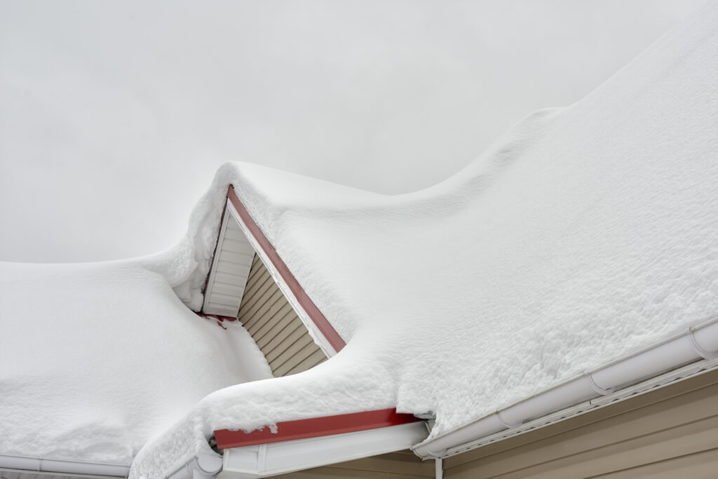 The roof of the house is covered with a thick layer of snow during massive snowstorm.