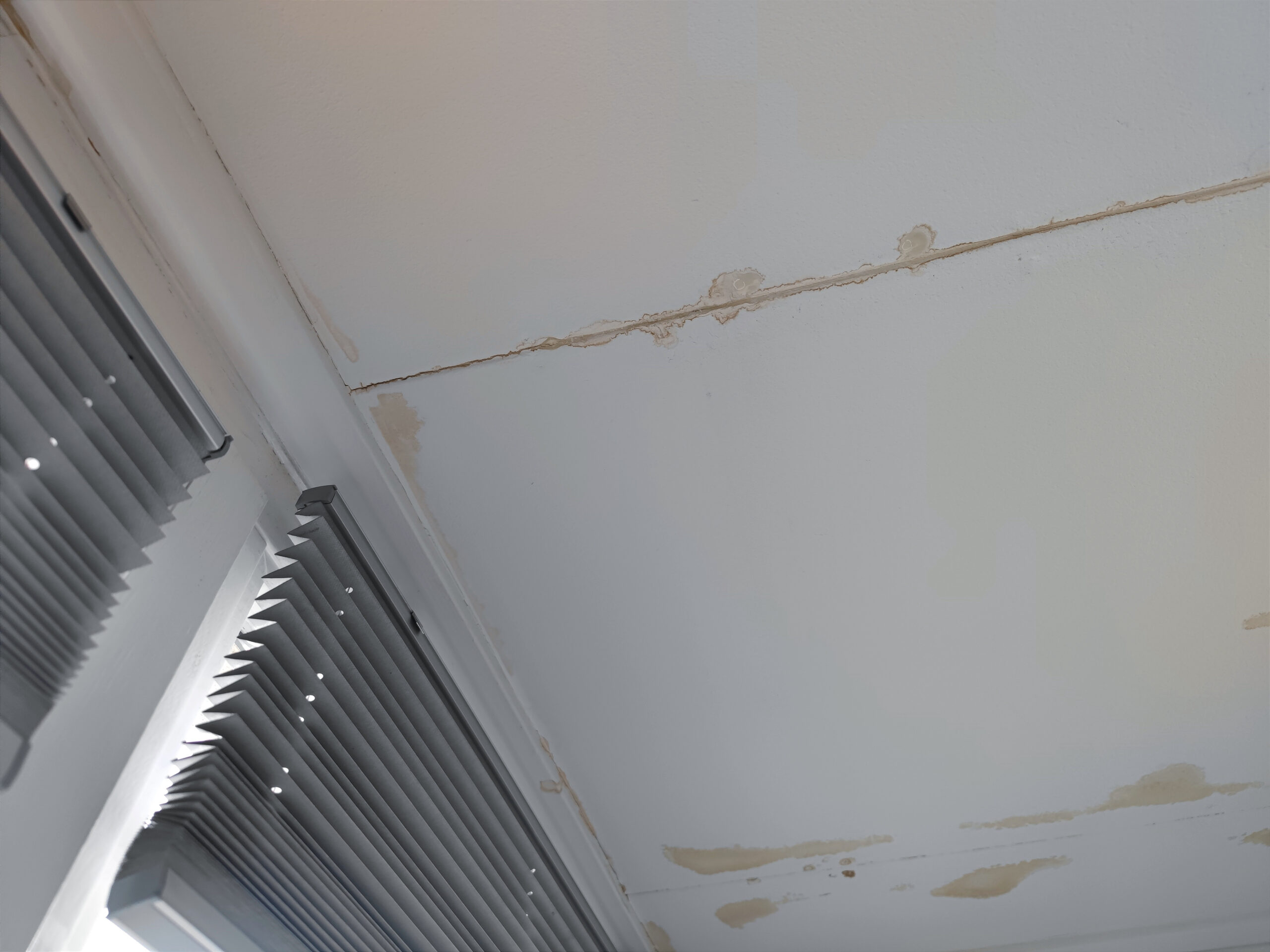 Wet spots stains from water leakage caused by a leak in the roof coming down through the ceiling and window frames