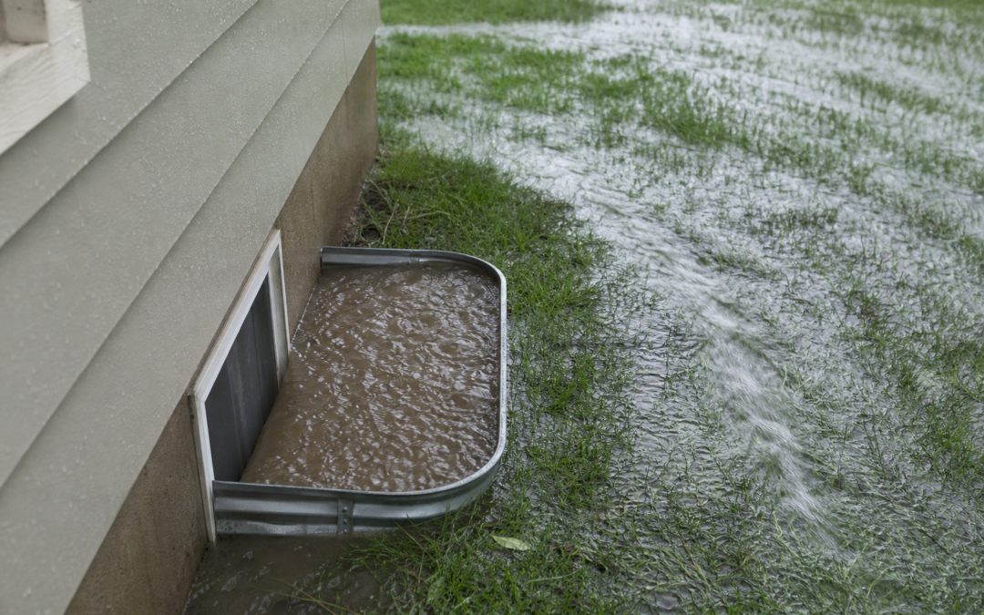 Window well filled with muddy rainwater against a Fort Collins Colorado home foundation during a storm